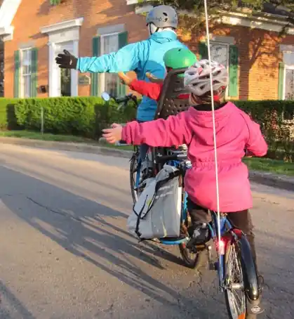 Verkehrsregeln Fahrrad: Familie auf dem Rad, die links abbiegt 