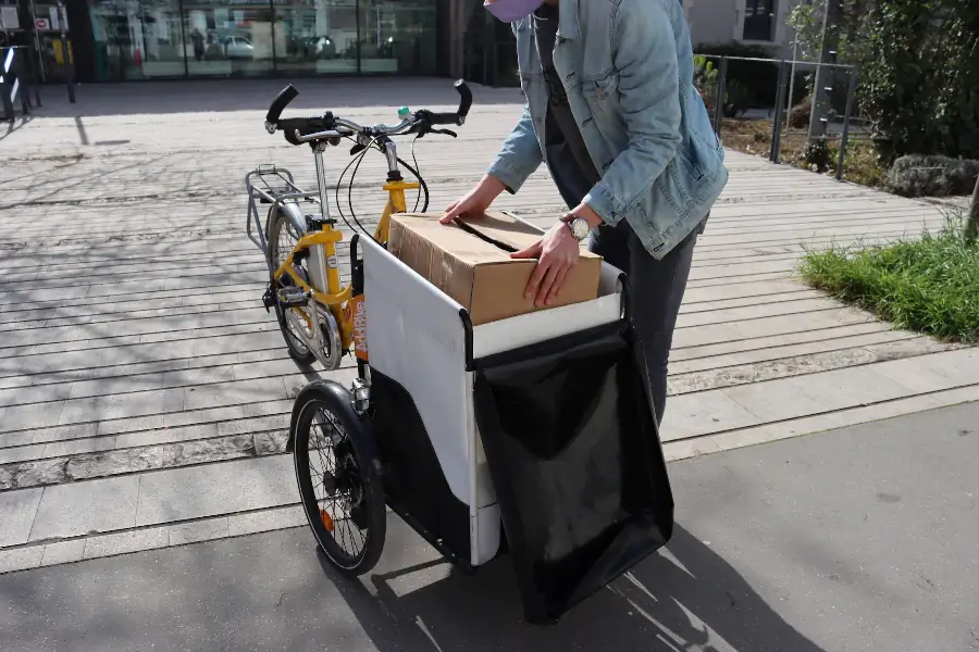 Man with bike with cargo box charging parcel at the front