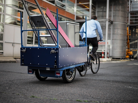 Une remorque vélo charge 100 kg avec des planches et une échelle