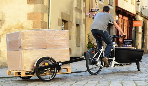 Une remorque vélo charge 100 kg qui transporte plein de boites en carton