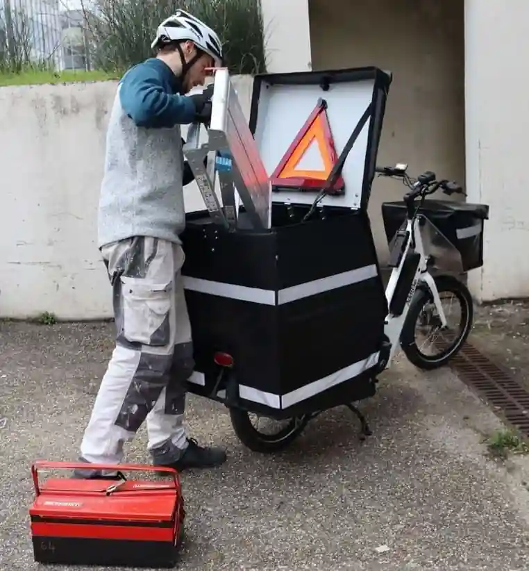 Un électricien remplit un vélo cargo électrique professionnel